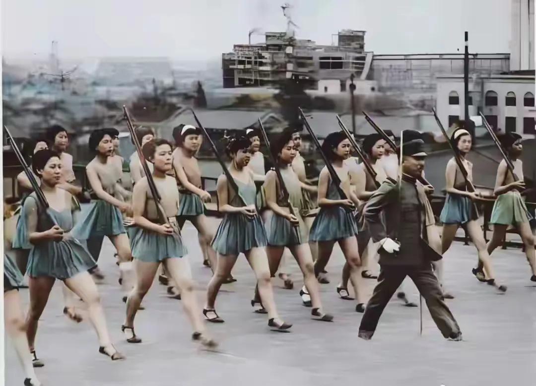 1942年东京，一群女高中生持枪列队操练，即将奔赴战场，为侵华战争服务。彼时倭奴