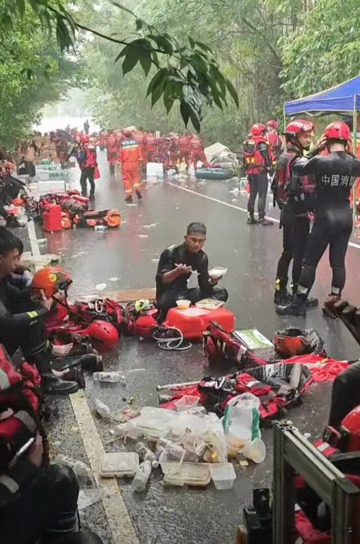 “泪目了”消防战士盘腿坐在地上吃饭，老天爷偏在这个时候又开始肆虐，雨又哗啦啦地下