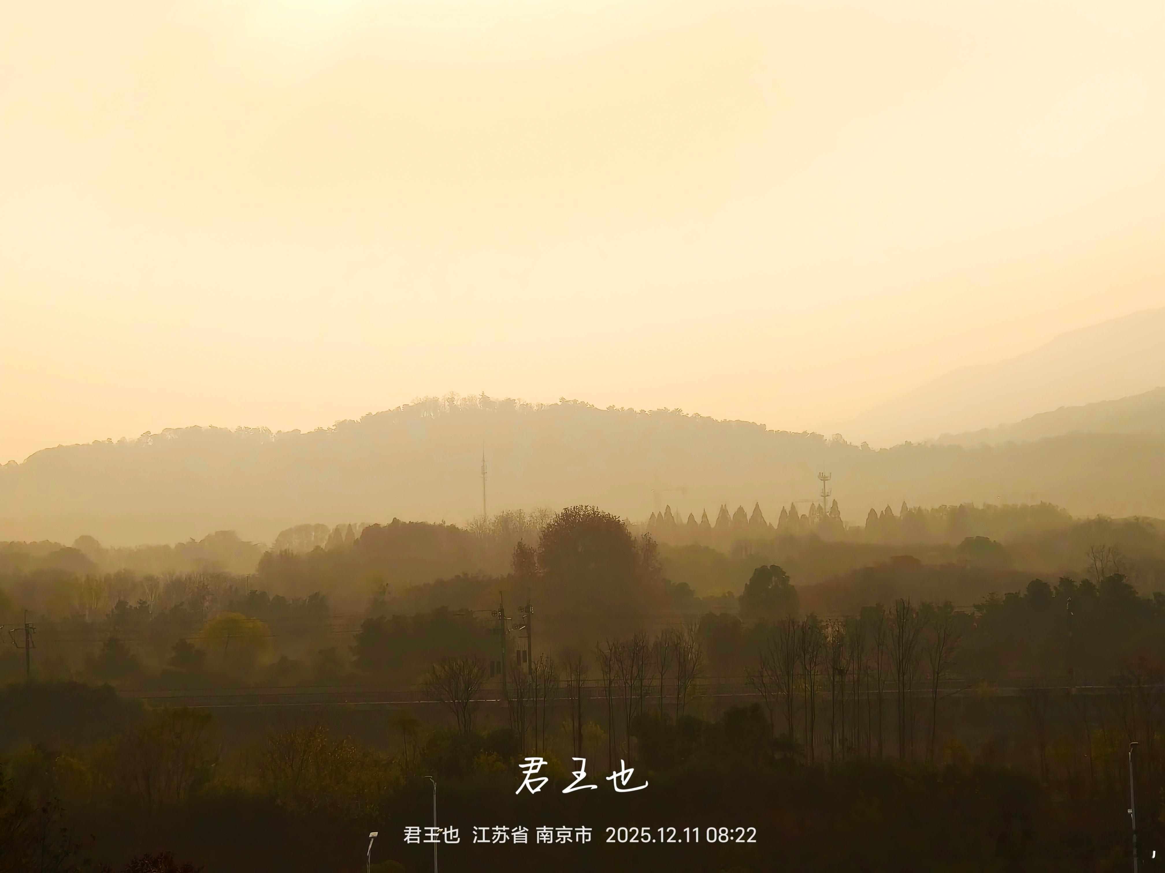 晨雾里的紫金山晨雾漫过紫金山的眉骨，把山峦揉成半透明的琥珀。晨光像融化的蜜，从天