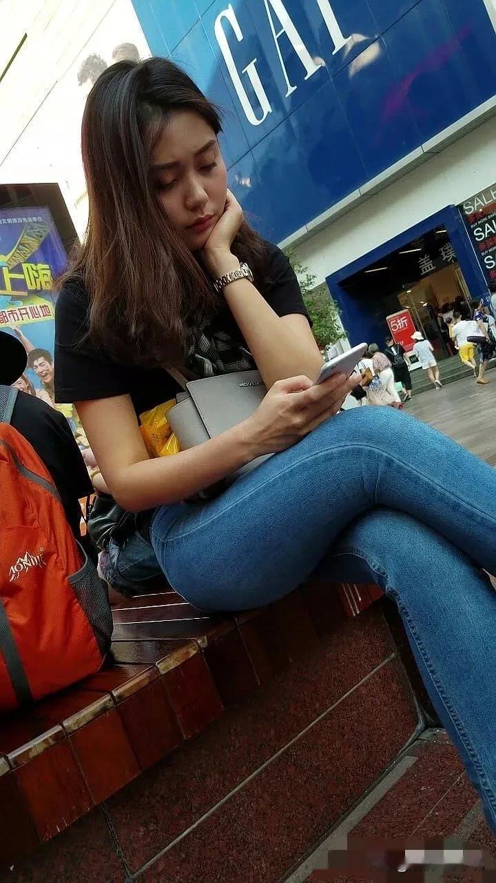 一对小情侣逛街走累了，坐在这里休息一下玩着手机，男友怎么斜眼看女朋友的手机呢！