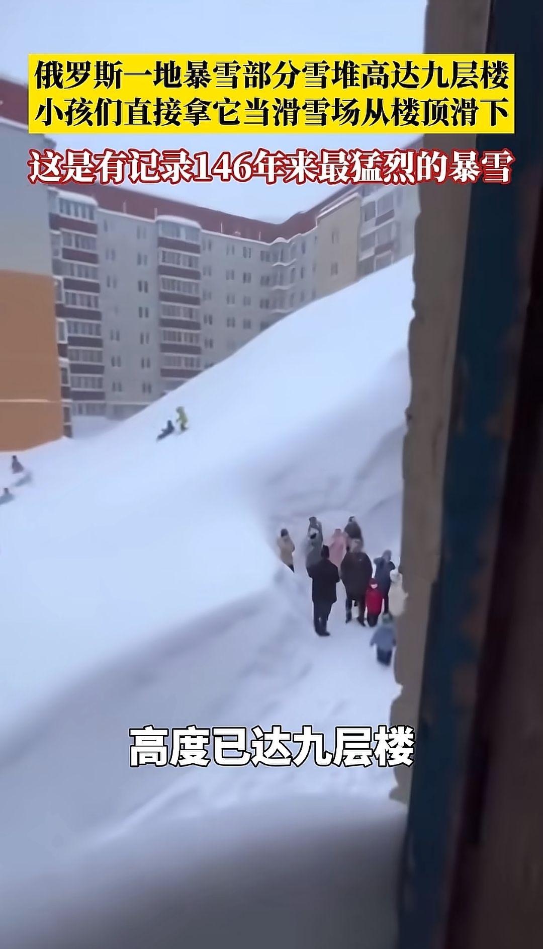 俄罗斯一地暴雪，部分区域雪堆高度已达九层楼，小朋友们直接拿它当滑雪场，从楼顶滑下