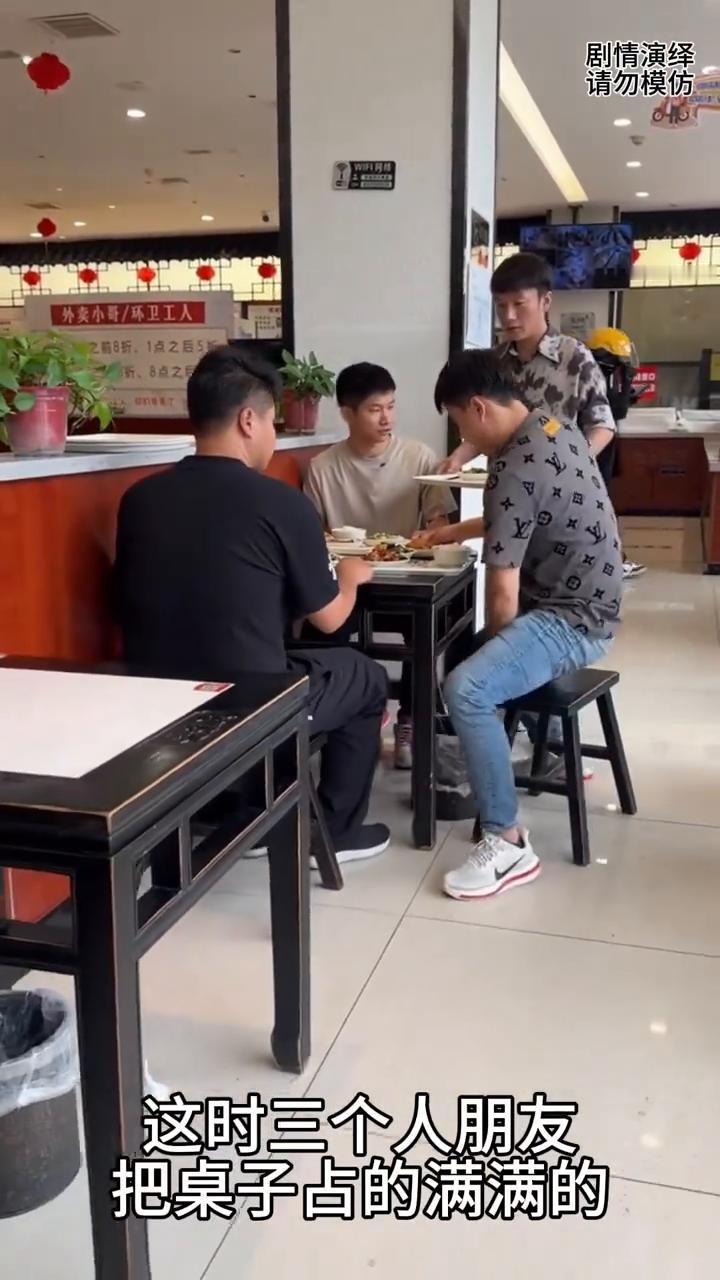 朋友们，端着饭菜准备一起吃。这时三个人朋友把桌子站的满满的，唯独第四个男子站在旁
