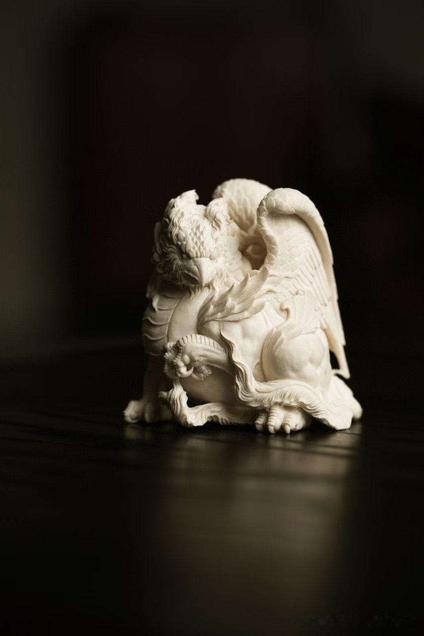 鹰的锐气，狮的雄健，在这件小巧的猛犸雕刻中融为一体。鹰首回望，喙如弯钩，羽翼层层