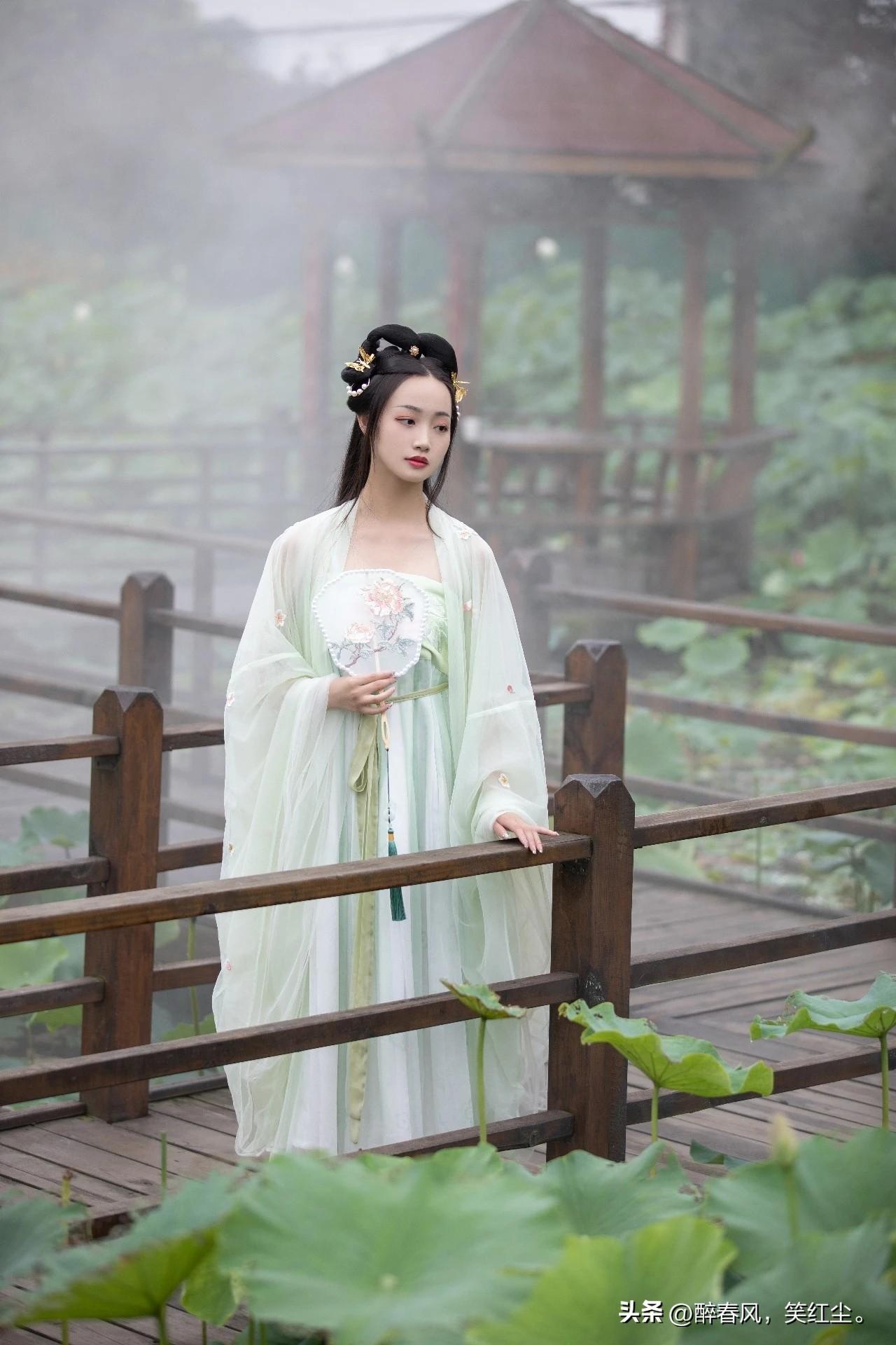 像是从山水画里走出的仙子。
身畔是碧波荡漾的江水，
身后是连绵起伏的青山。
不需