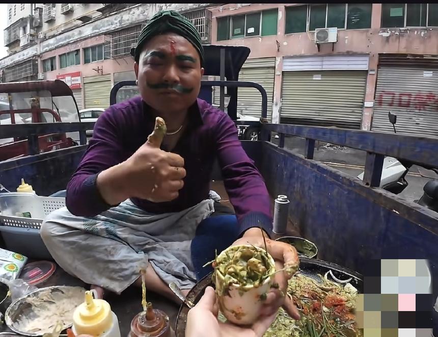 模仿印度的小商贩，应该是咖喱鸡蛋饼，面粉整的满脚丫子都是，把印度人这个埋汰劲，演