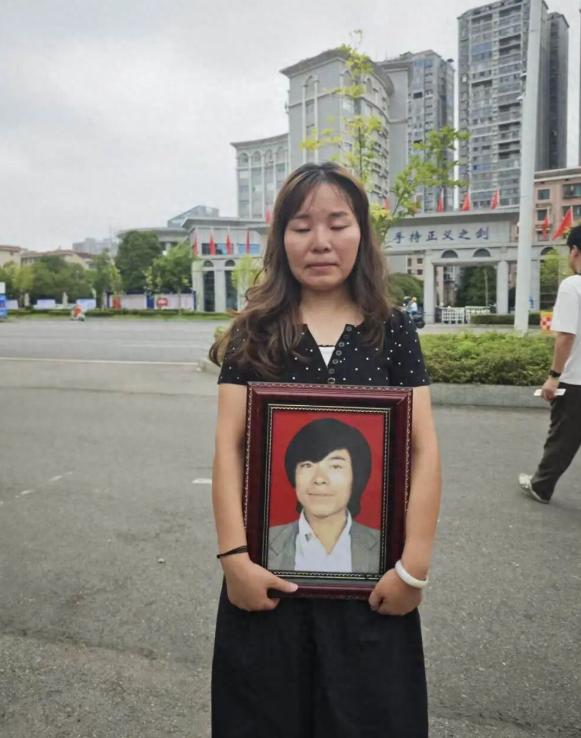 27岁摩的师傅跑活遭劫杀，凶手潜逃30年才抓到，宣判当天女儿抱着父亲照片站在法院