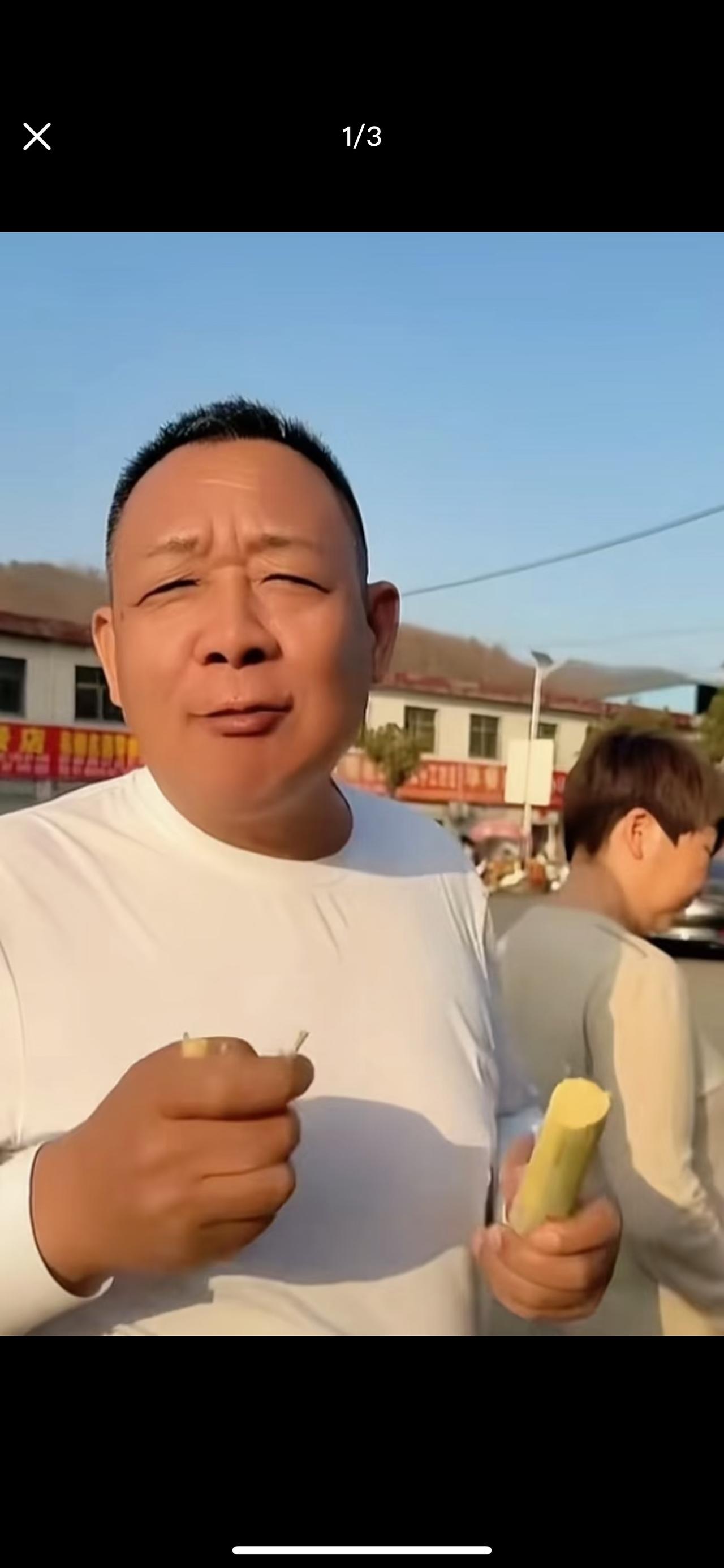 于东来在南阳街头啃甘蔗，难得这个岁数牙口还这么好。

从照片中看，于东来穿着白色