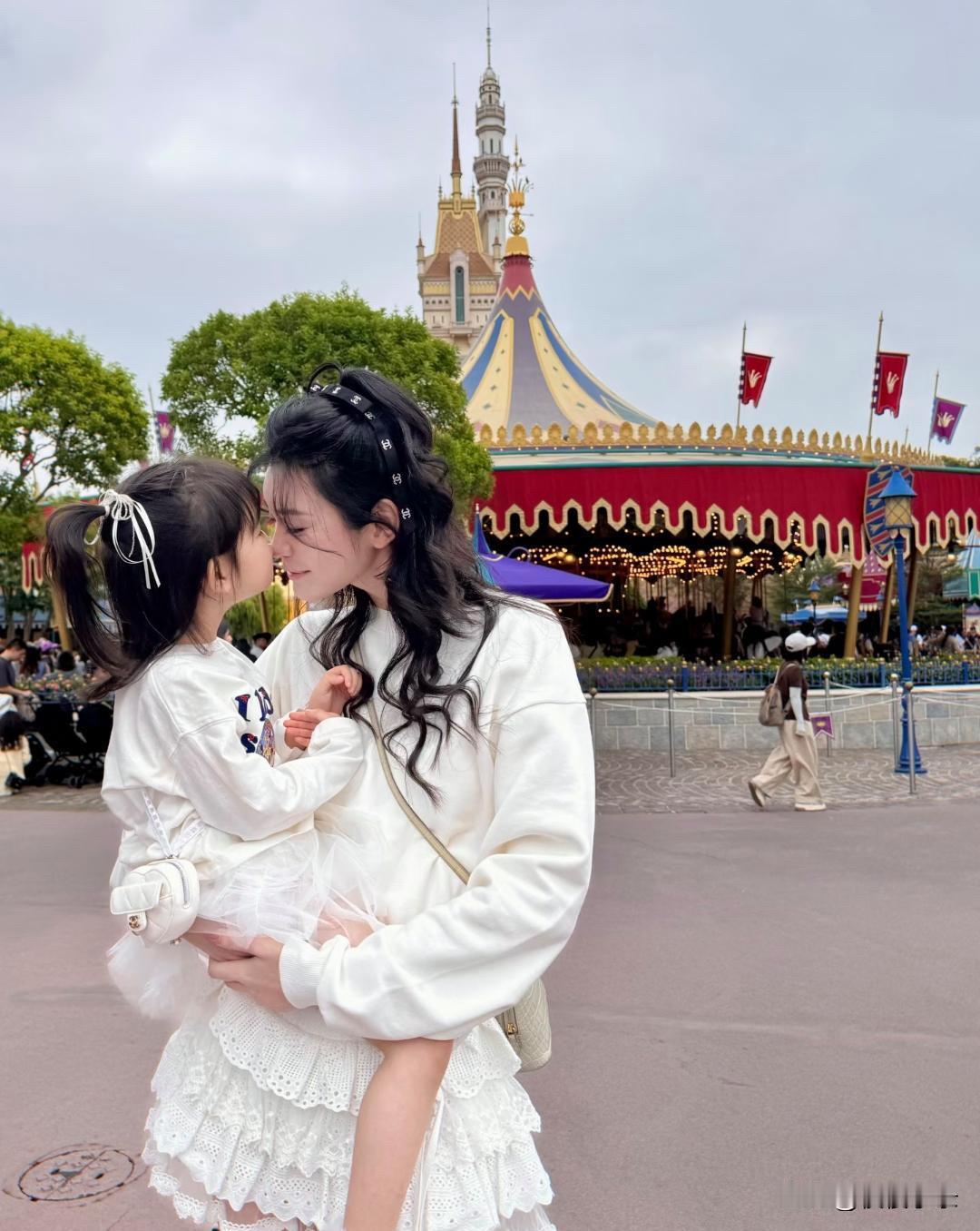 奚梦瑶何猷君一家四口到迪士尼乐园玩，奚梦瑶抱着4岁女儿，两人穿着母女装，看起来好