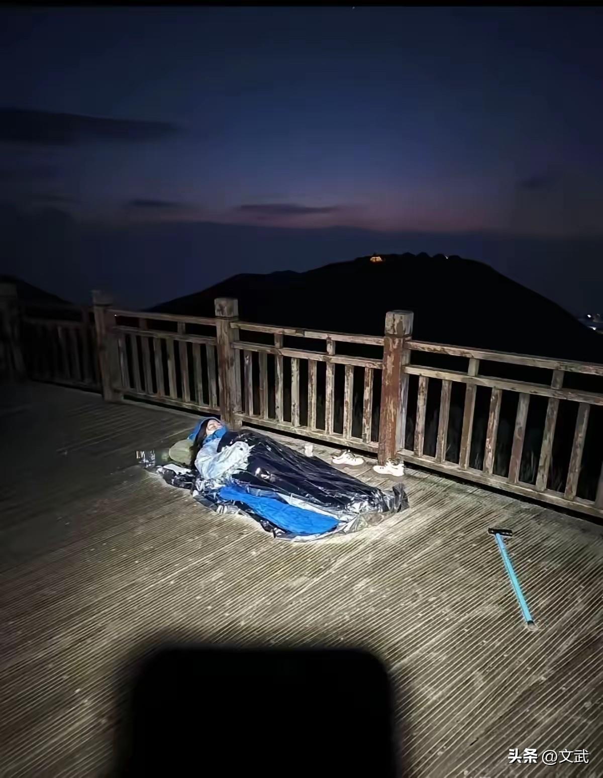 武功山露天裹睡袋等日出，不能拿安全当赌注‌，一名女子直接躺在观景平台的睡袋里，连
