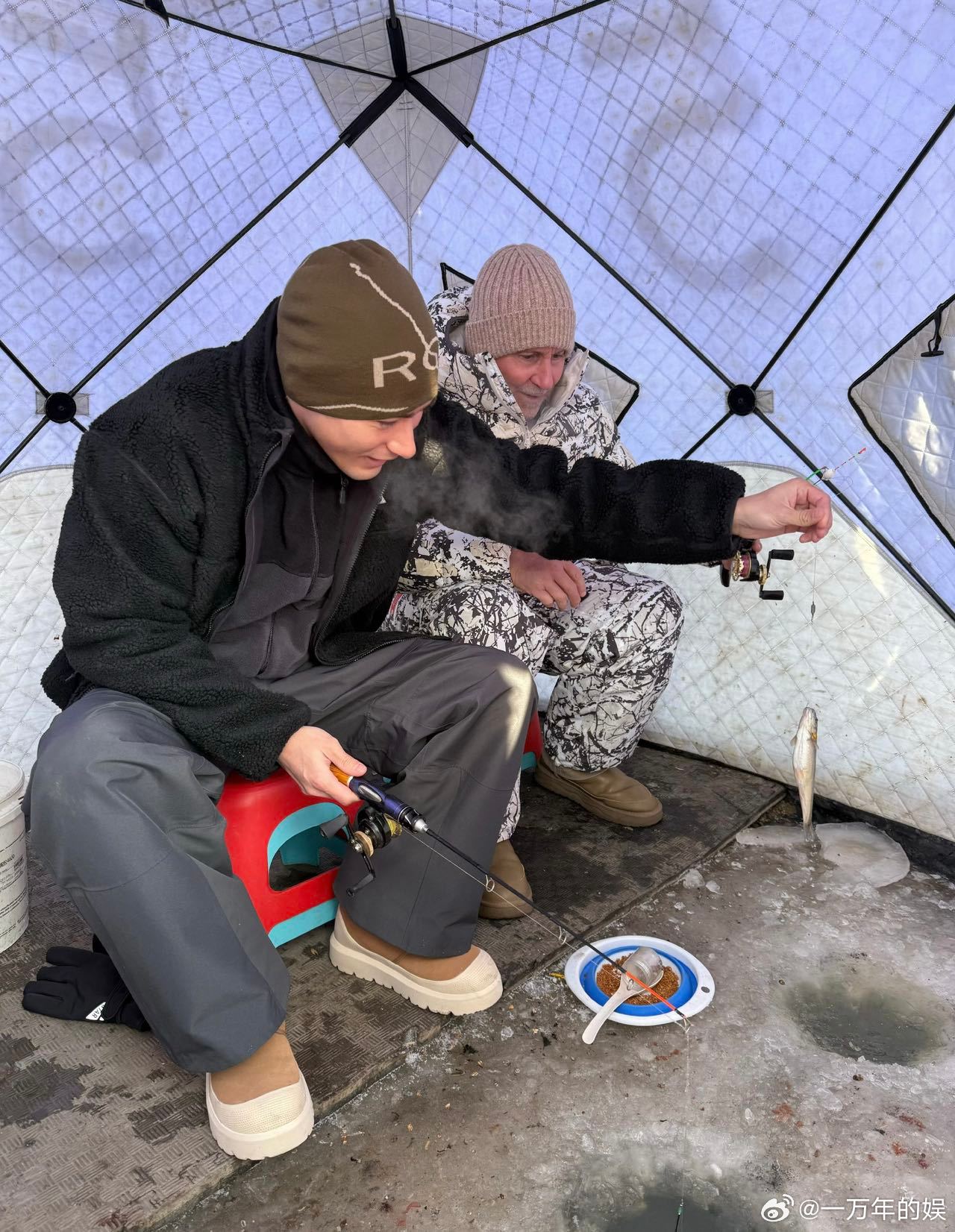 米卡父子东北游vlog 冰钓时米卡给爸爸递暖手宝，自己冻得搓手，爸爸把他的手揣进