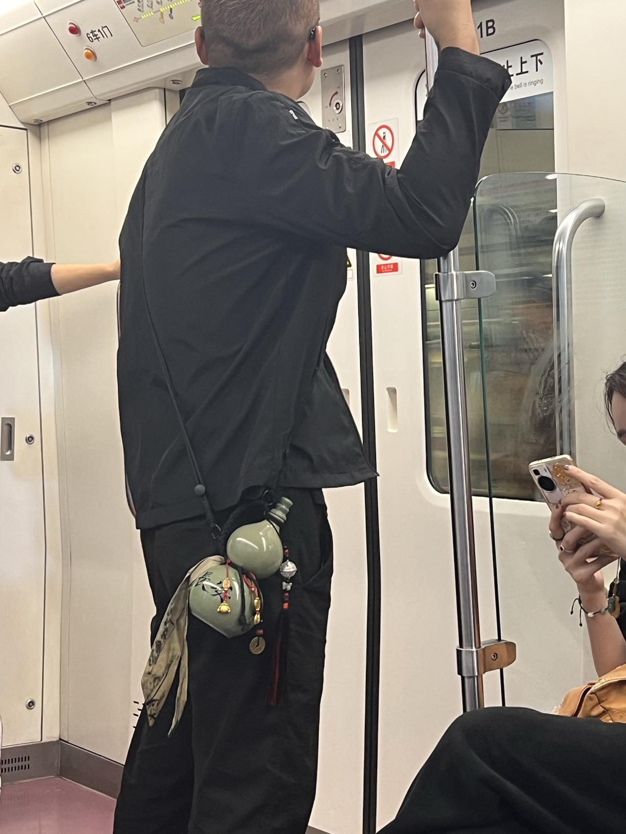 在西安地铁的现代空间里，他腰间的古风酒囊似是时空的褶皱。当城市的风掠过车厢，那一