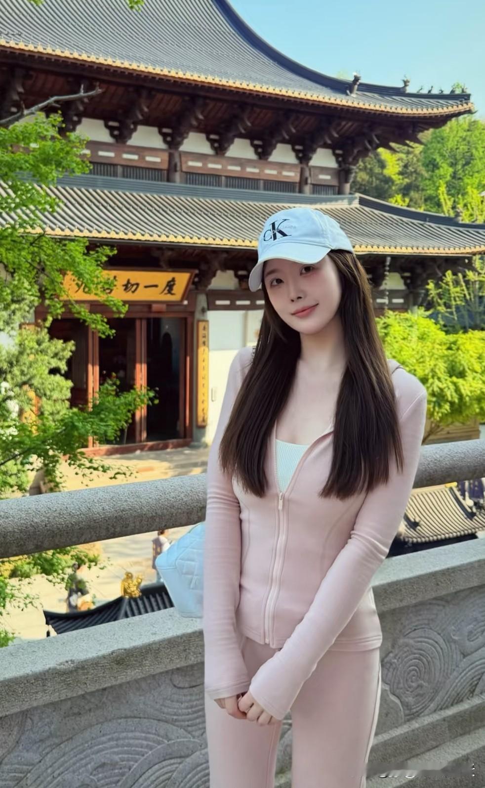 在古风建筑前，一个少女的背影宛如一幅绝美的画卷。她身着淡粉色的古风长裙，裙摆随风