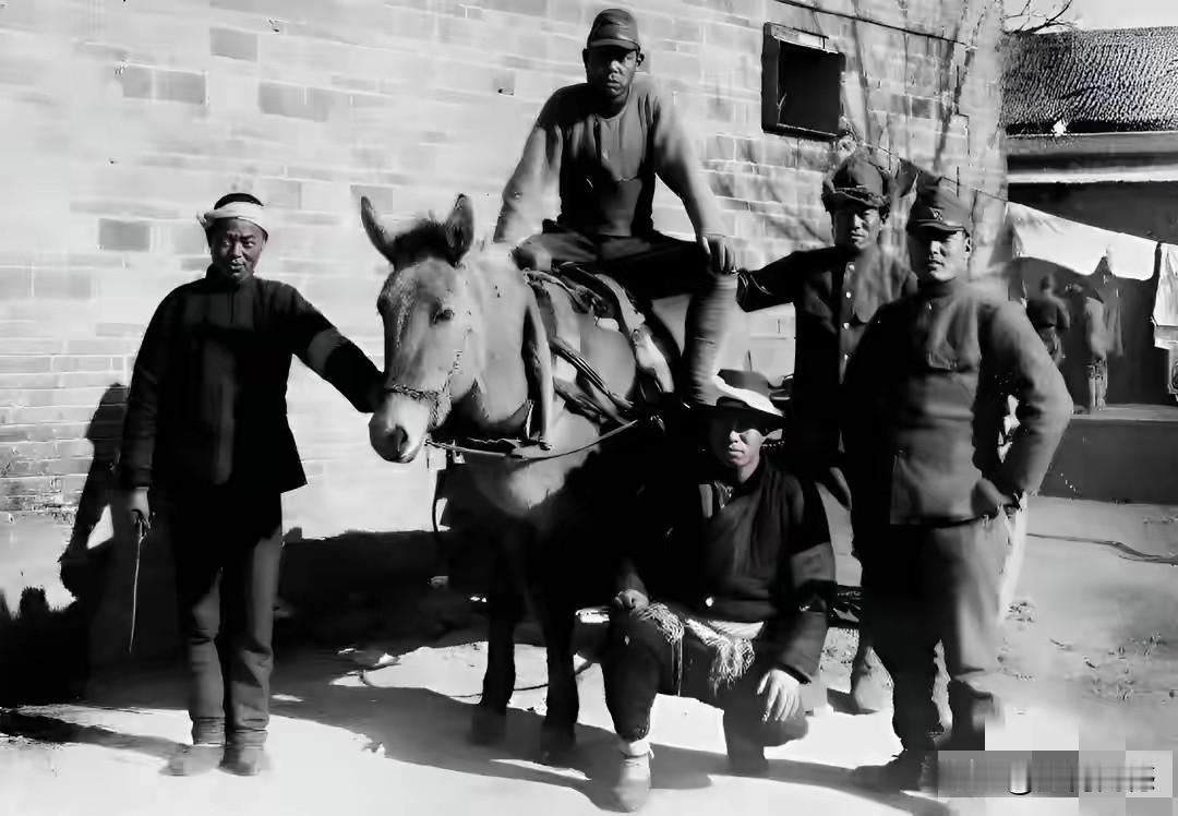 这个日本鬼子骑在马上，一只脚好像蹬在蹲在地上的这个人的肩膀上，另一个人给它牵着马