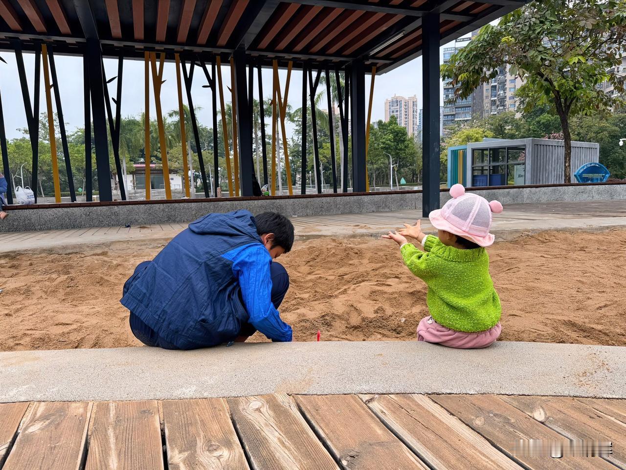 其乐融融！蒙蒙细雨中，弟弟和妹妹在一块儿玩沙土。