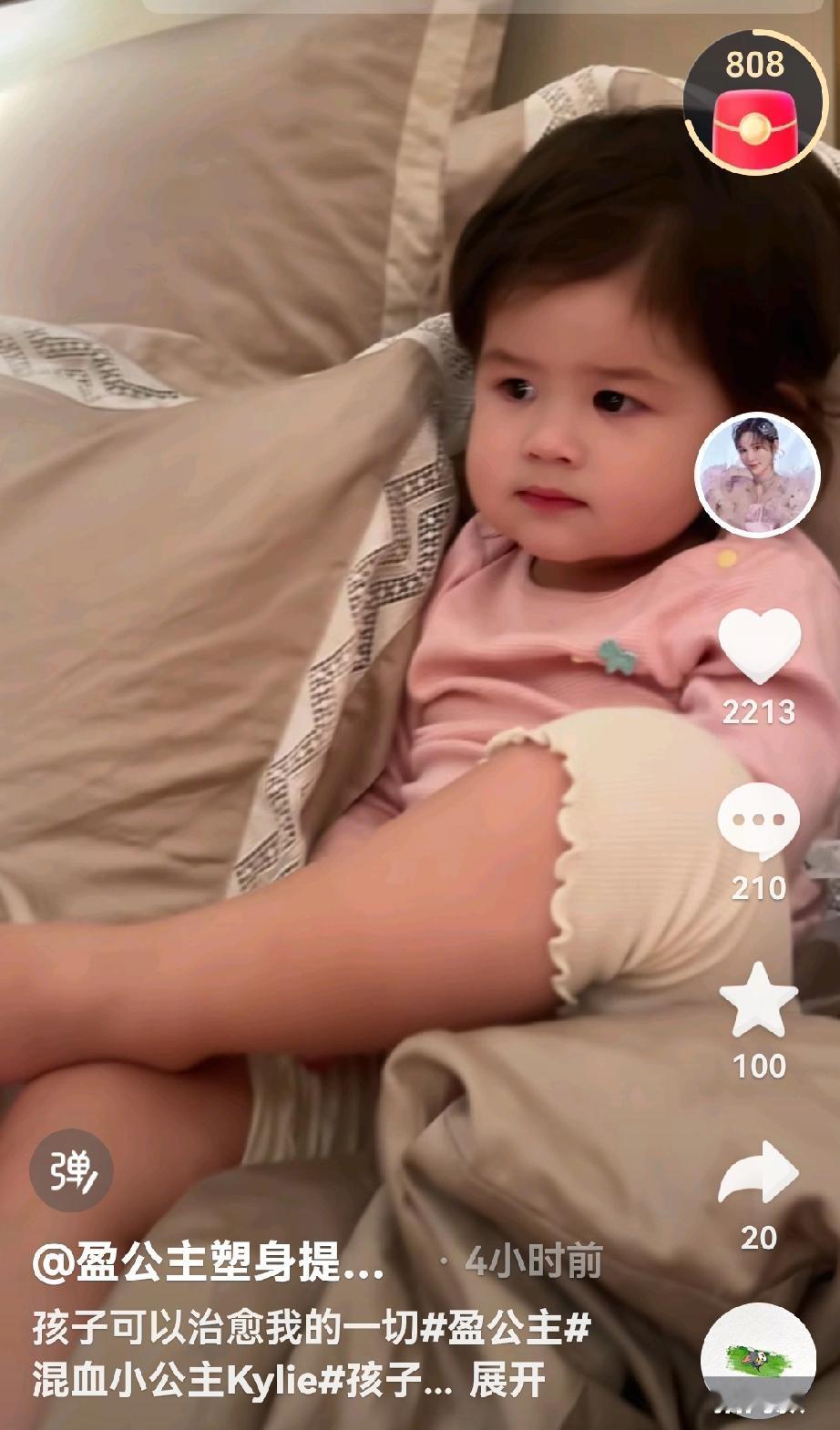 小凯莉乖巧的坐在床上看电视，还翘着二郎腿，很像爸爸的风范，还懂事的帮妈妈搬东西，