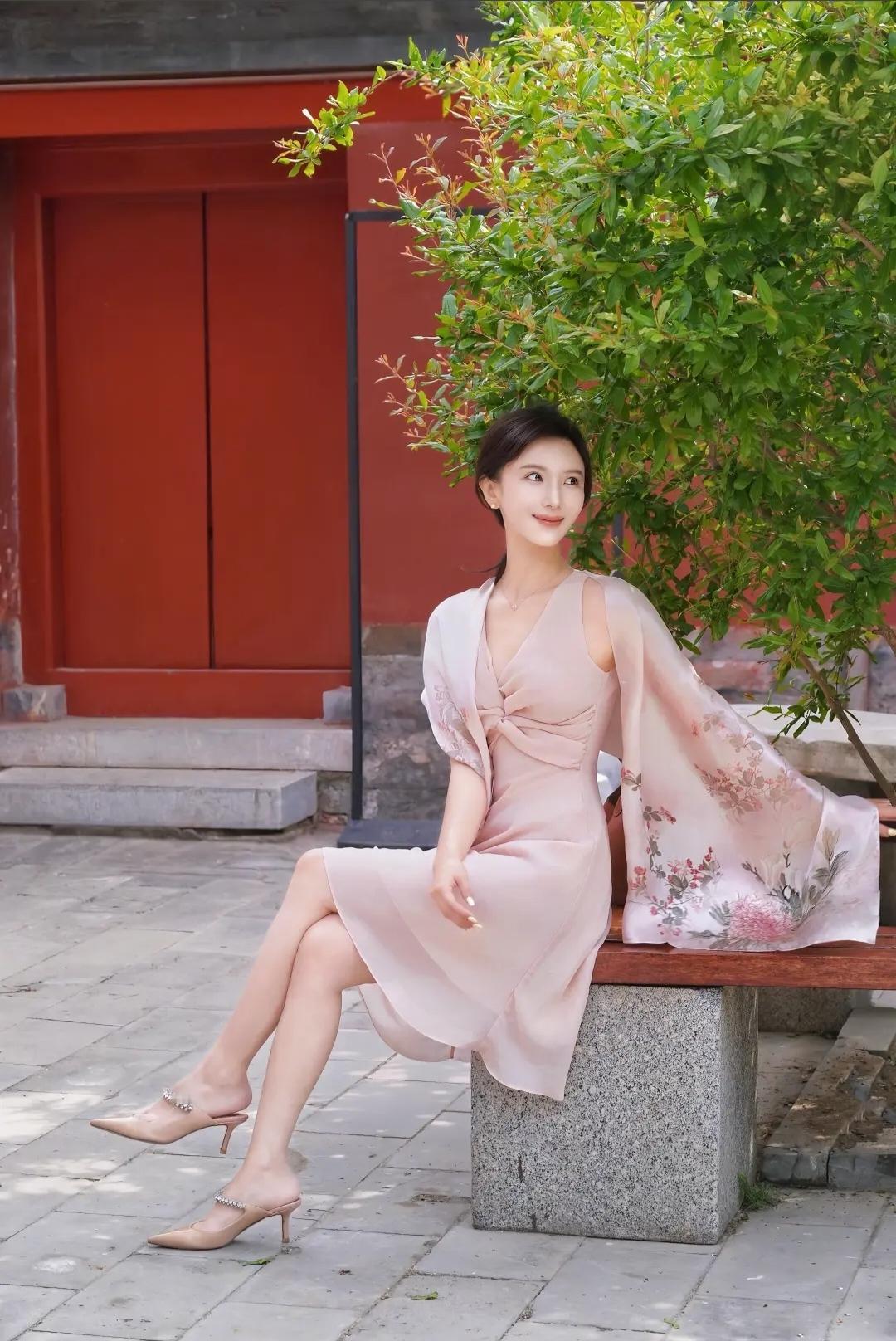 优雅坐于古风庭院，粉色长裙与高跟鞋相得益彰，尽显东方韵味。