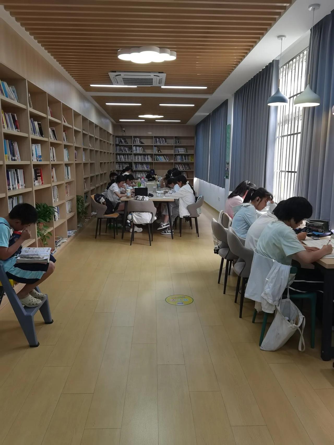 下午去图书馆借书，阅览室的空位上坐满了小学生，他们不是在看书，都在专心致志地做暑