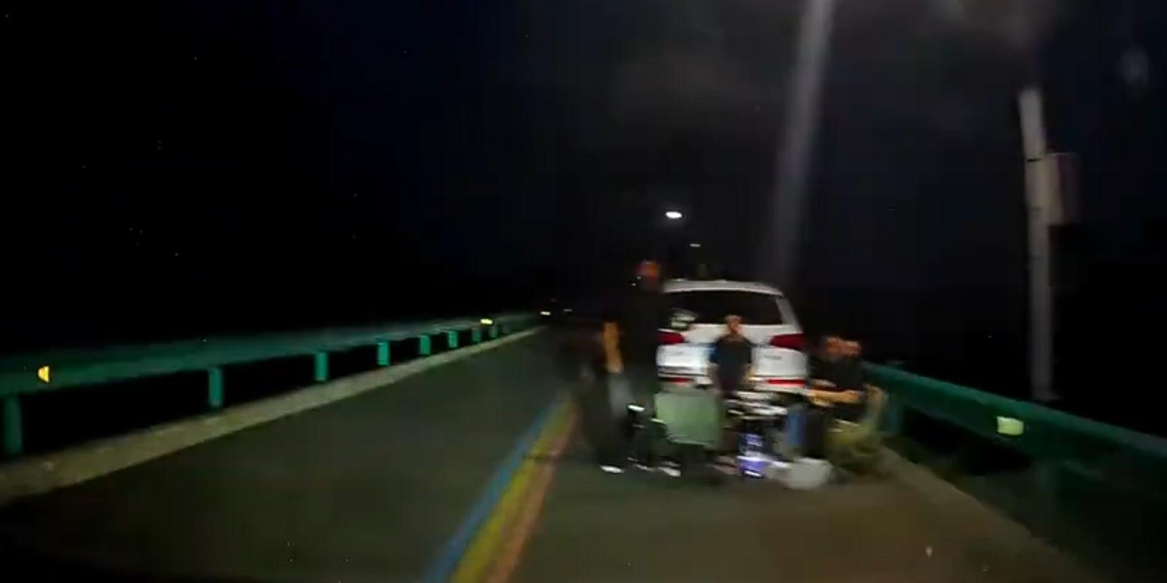 司机避开远光灯惊见多人车道聚餐 对向车道远光灯晃人眼，同向车道四个人坐着吃席。这