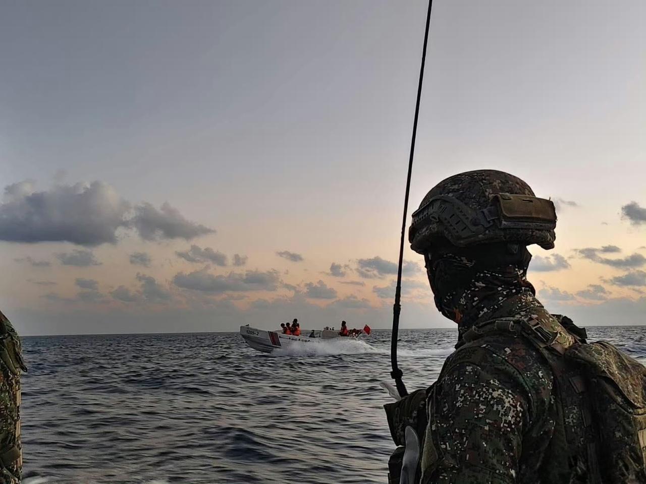 中国海警5205舰的舰载工作艇在中业岛岸边驶过，近景是岛上的菲律宾海军陆战队士兵