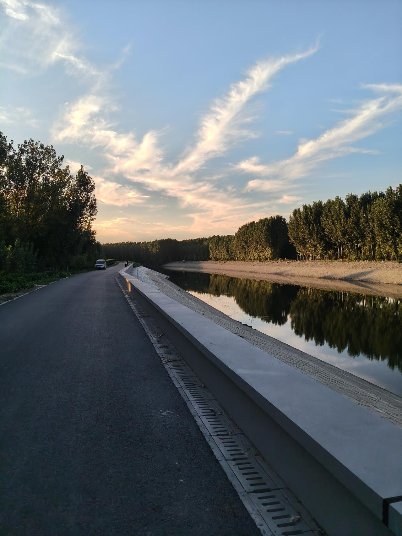 晚饭过后一个人骑着自行车在河边自由活动，看着滚滚落下的夕阳，看着平静的河面，道路