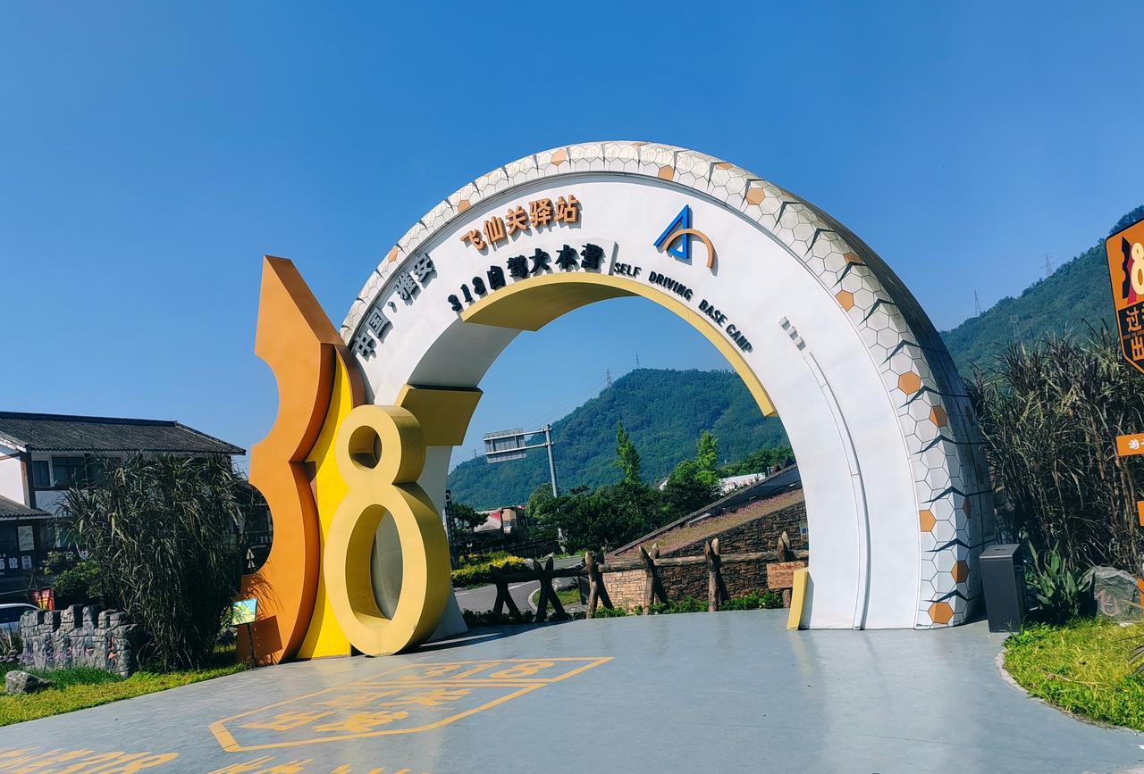 踏入雅安飞仙关驿站，巨大的318国道起点拱门静静矗立在蓝天下，橙黄的数字“318