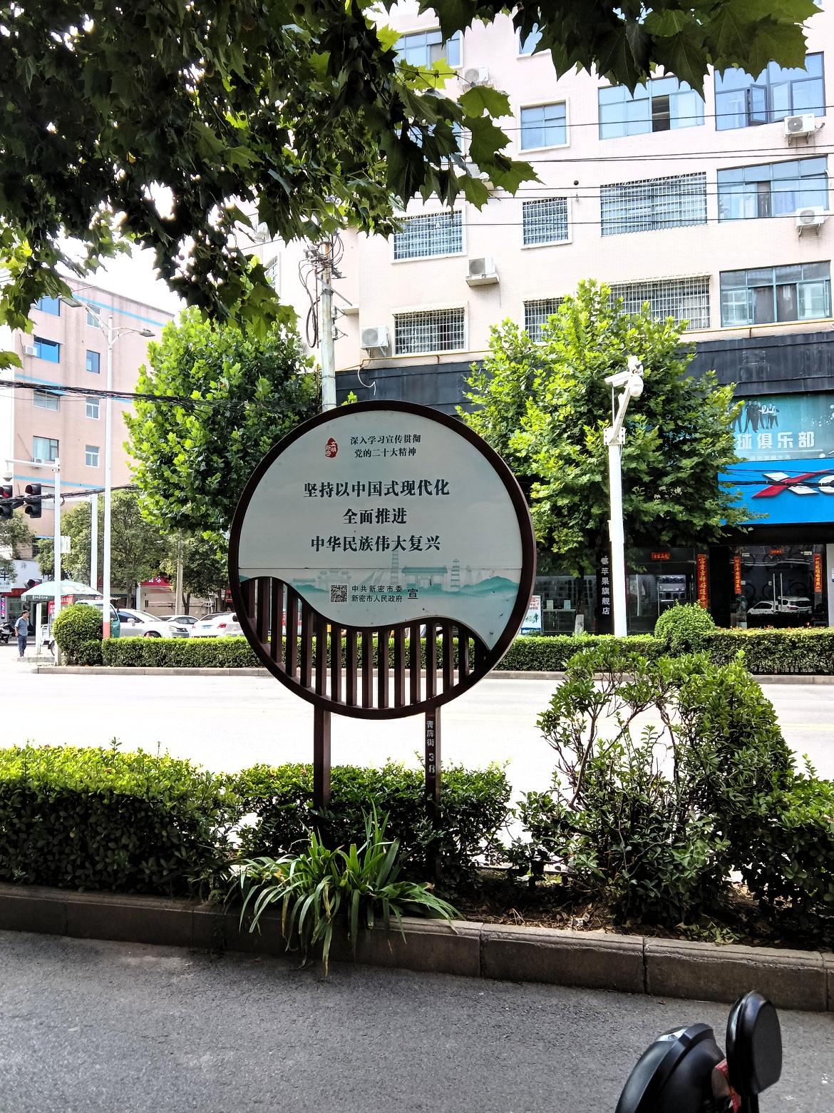 这是新密街头一块宣传标语牌。上面写着：坚持以中国式现代化，全面推进中华民族伟大复