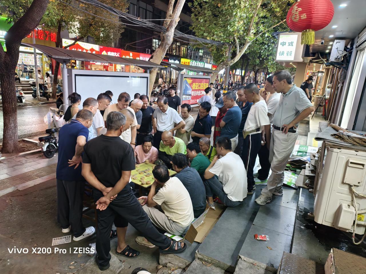 这是刚刚我在广巴路上拍的，两个棋手下棋，一群人在观看。
