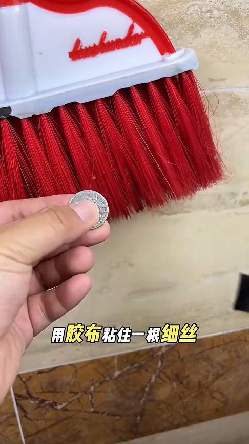 拿一枚硬币放在扫帚上，用胶布粘住一根细丝，然后把这根细丝剪下来放在硬币的背面，用