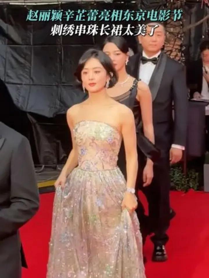 赵丽颖闪耀东京电影节红毯，身着闪钻长裙，光彩夺目。她亲切微笑，与粉丝互动。此行旨