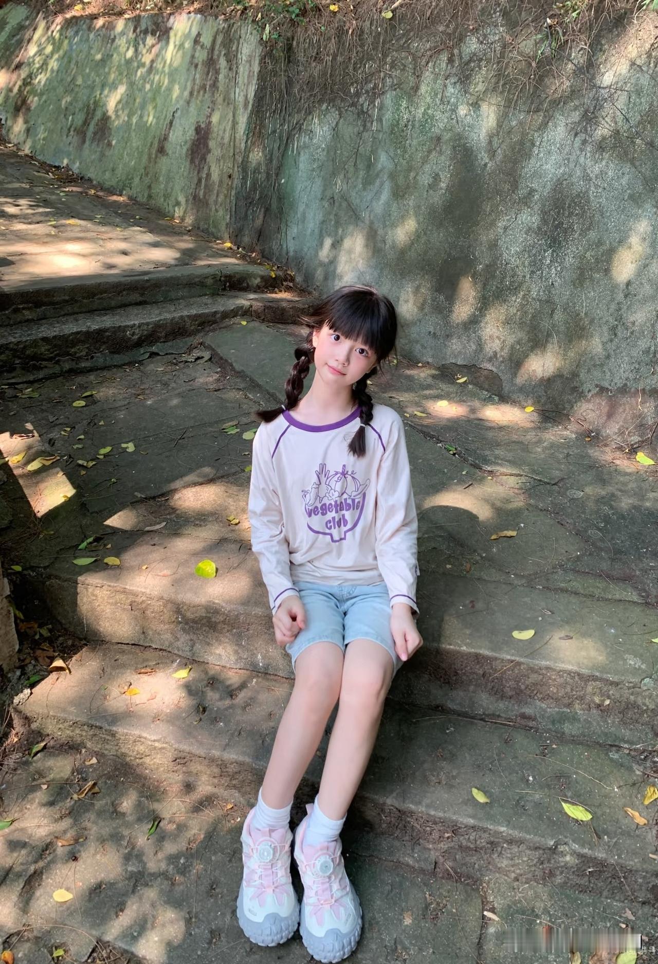 小妹妹坐在台阶上，笑眯眯的。