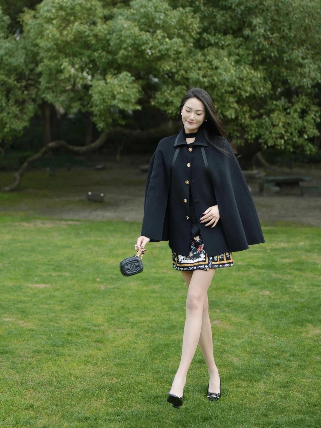优雅漫步在绿意盎然的公园，黑色大衣与印花短裙的完美搭配，尽显时尚与自然之美。