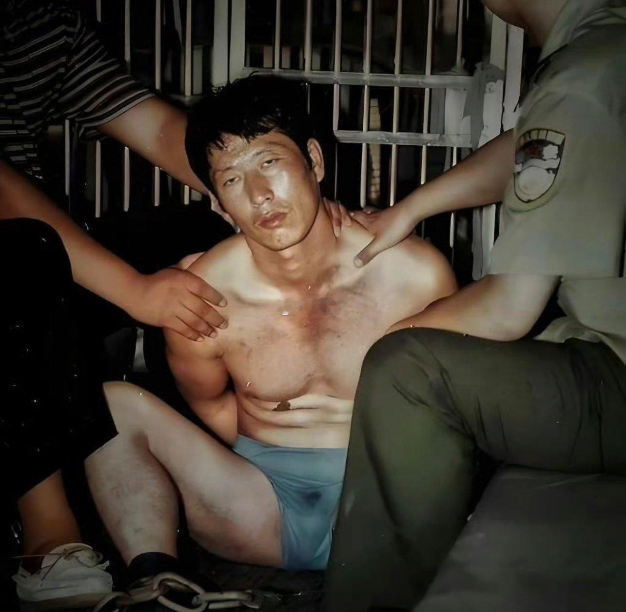 1997年，“悍匪”白宝山被警方控制的现场。他穿条裤衩，双手反铐，脚上有镣铐。 