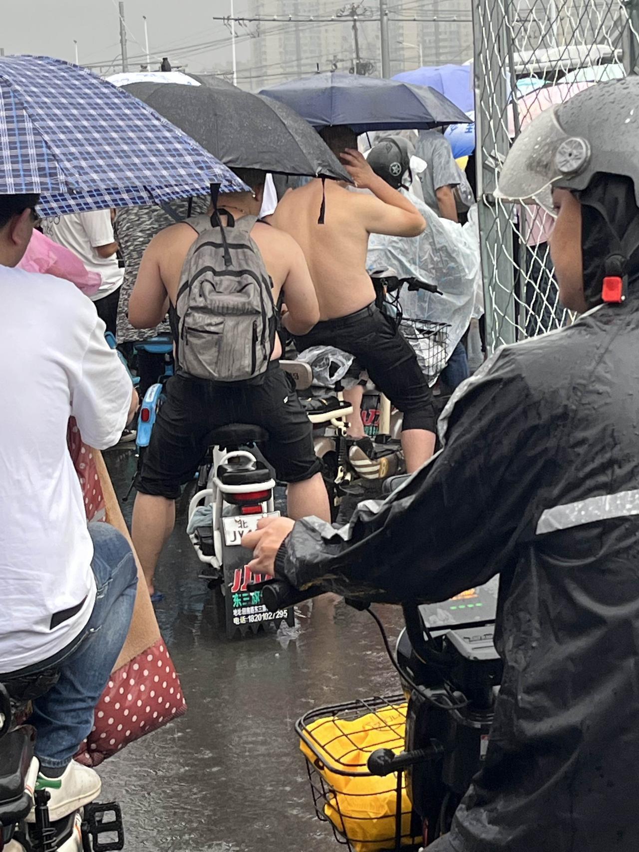 今早北京大雨，路口过红绿灯时，看到两壮汉赤膊上阵，一人骑一电动自行车，在人群中很