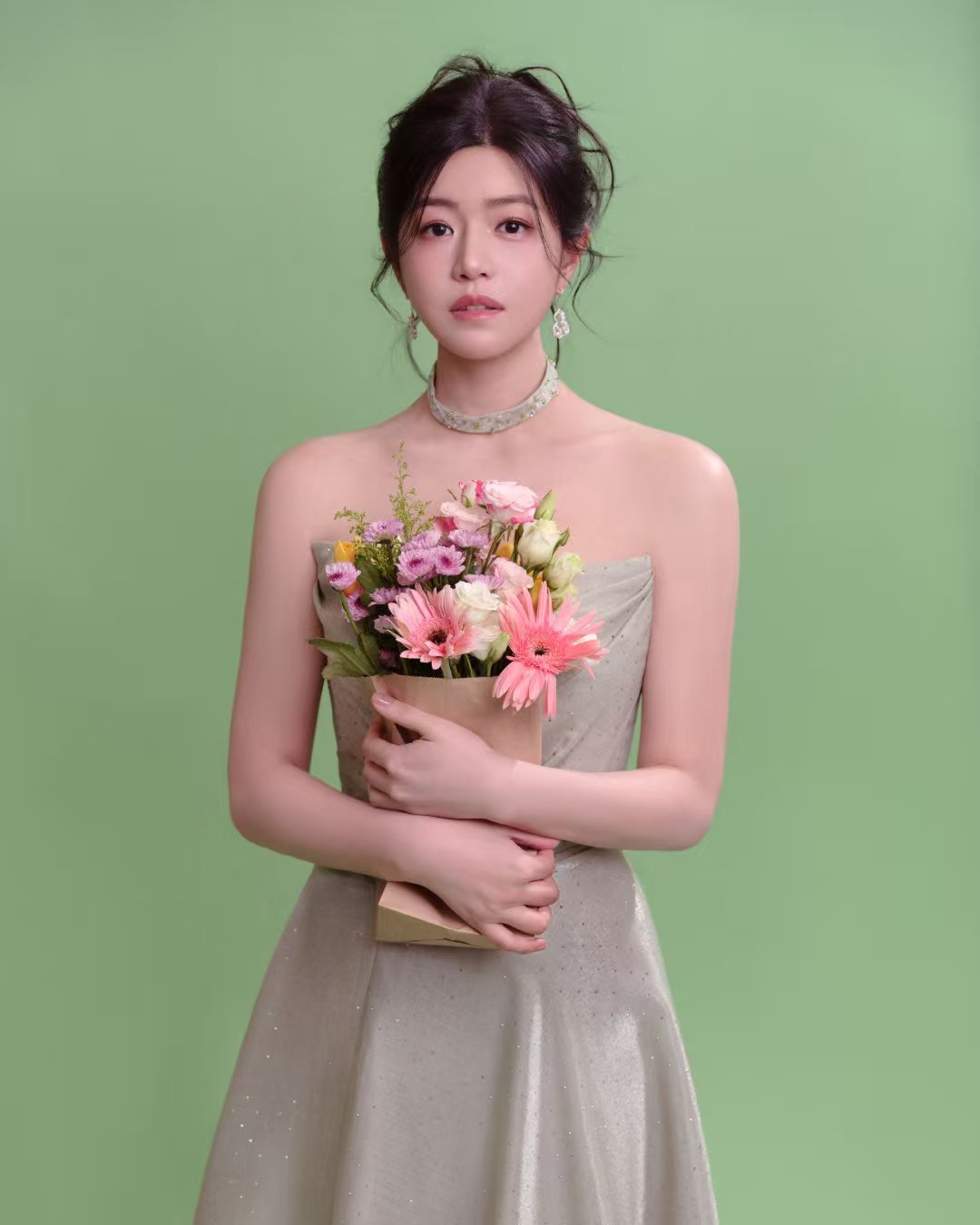 柔光染裙，繁花入镜，身着鎏光缎面长裙，在绿意间拥花而立。风止于此，花为她开，时光