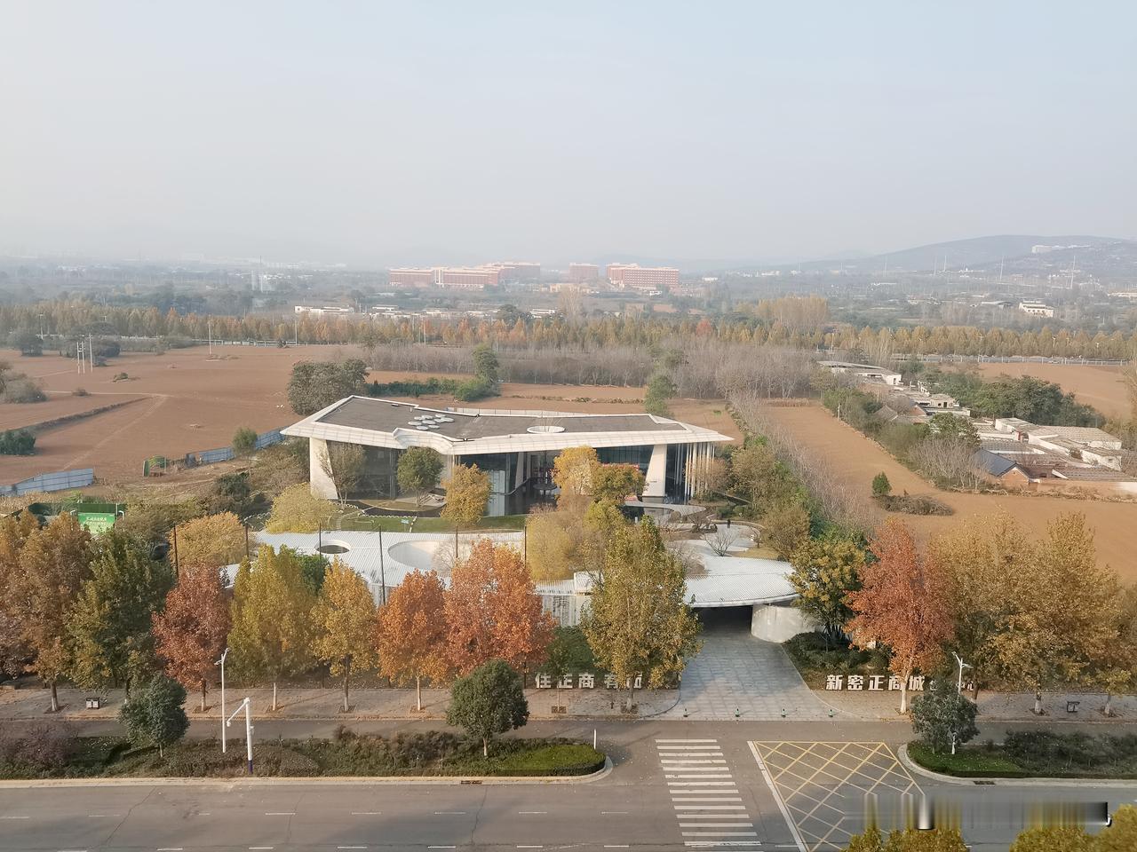 这个视角瞅着还真敞亮！底下这栋楼看着特现代，玻璃墙配那平屋顶，造型还挺洋气。楼周