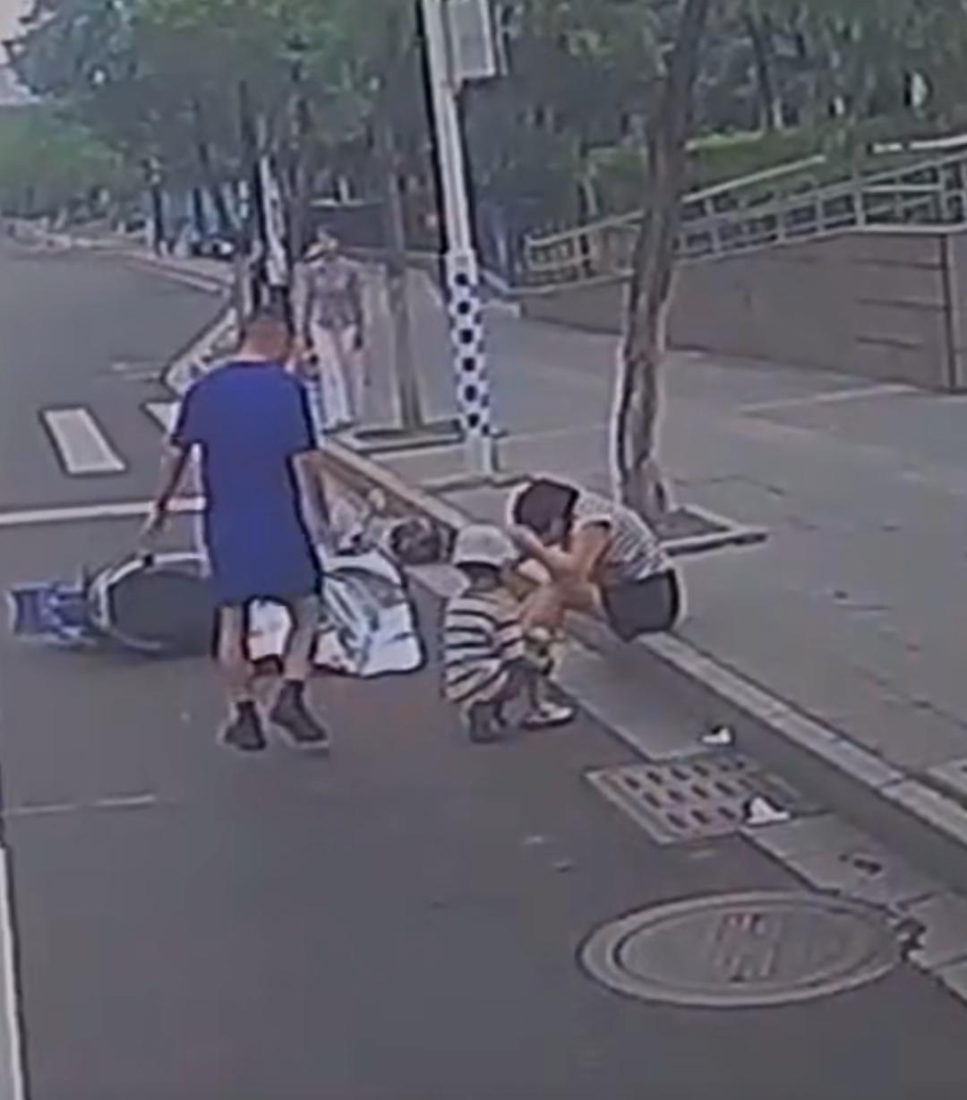 6月4日的江西赣州街头，阳光灼热，一位母亲带着孩子骑车时不慎摔倒，母子俩狼狈地跌
