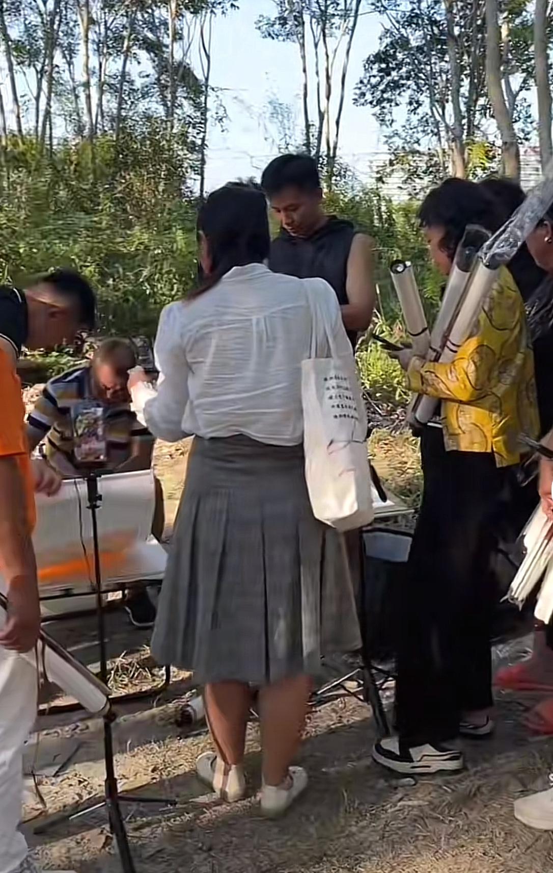 今天沈巍在另一个地开笔写字画，四周树木茂密，他在里面的一个空地上摆摊。

在现场