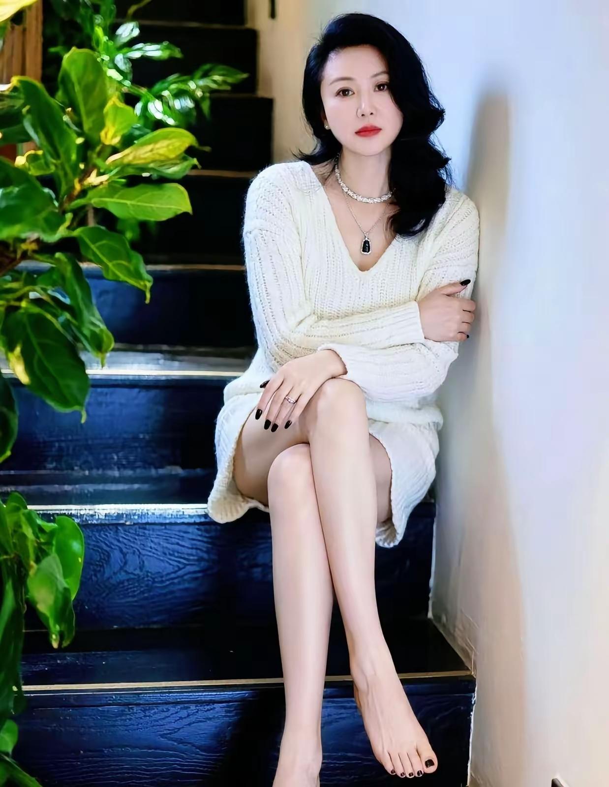优雅黑发美人，静坐深蓝楼梯，绿植映衬，时尚与自然的完美融合。