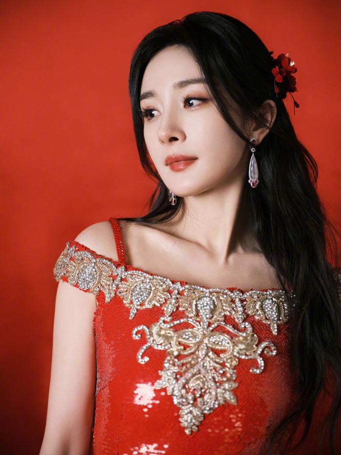 杨幂身穿红色亮片裙在阳光的照耀下闪闪发光，把杨幂衬托得明艳动人。她那精致的妆容和