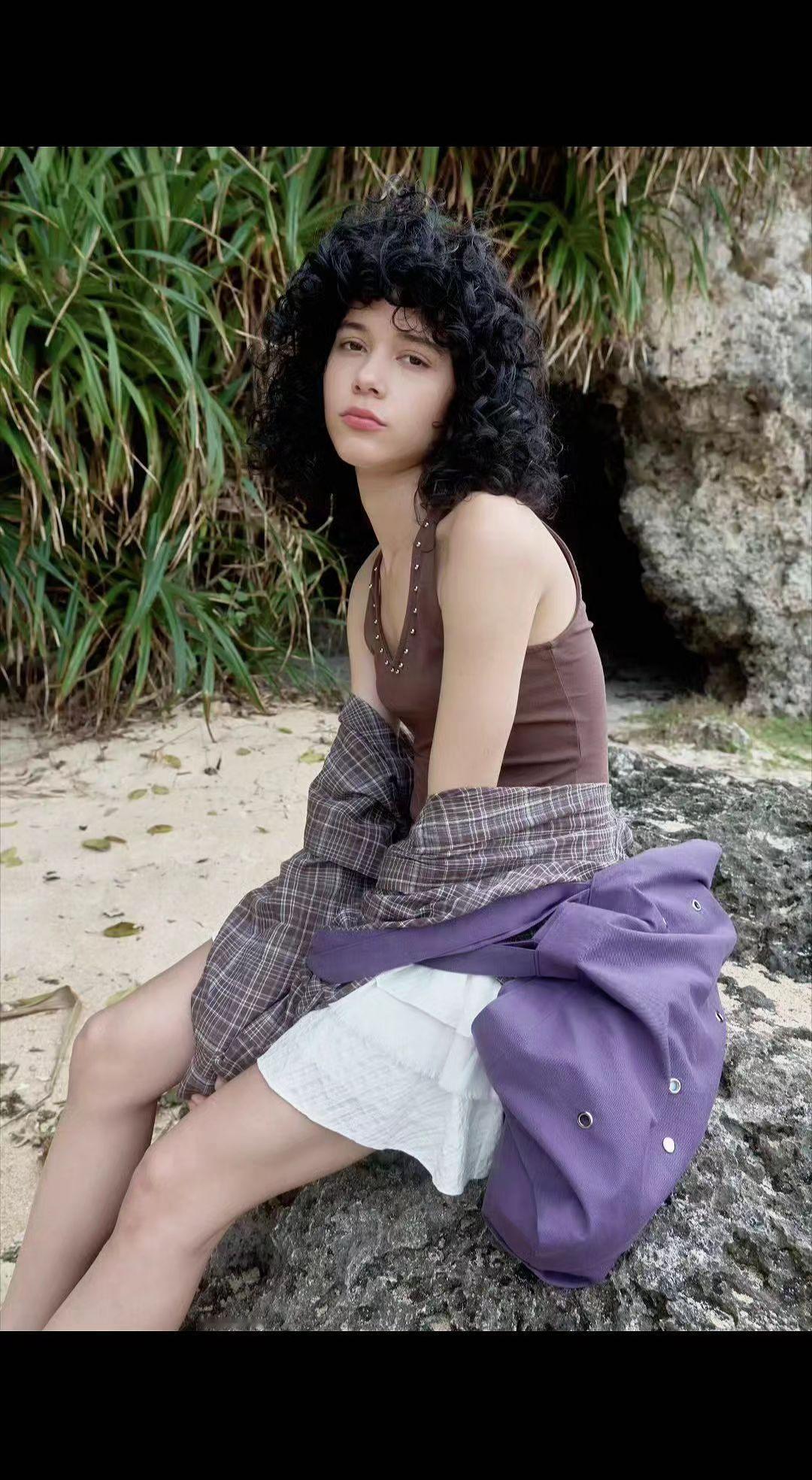 🌿礁石上的慵懒，像被海风吻过的诗。卷发藏着潮汐的秘密，衣角兜住整个夏天🌊