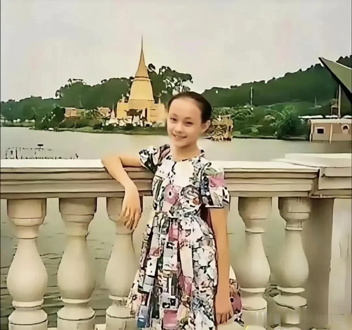 这个小女孩最特别的地方就是额头比较高，她穿着一条连衣裙，站在湖边的桥上留下了这一