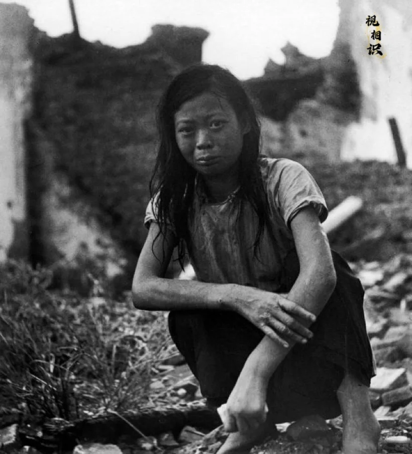 1938年，日军飞机轰炸完广西桂林后，一名妇女蹲在自己完全被毁的房屋前，脸上满是...