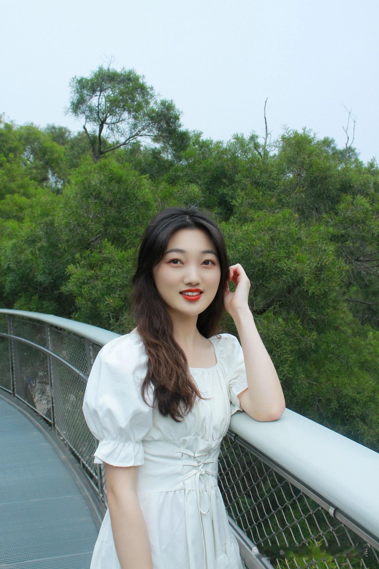 一位穿白裙的女孩在桥上微笑。