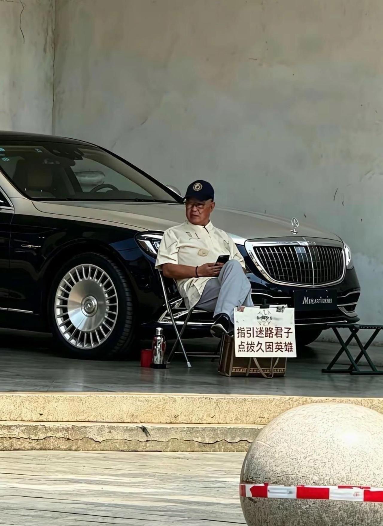 大爷这摊直接是顶配版排忧解难业务，别人摆摊蹬三轮，他直接迈巴赫当背景板。
牌子写