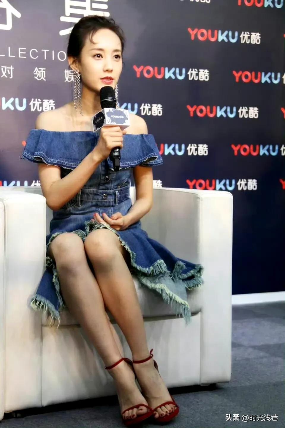 坐在舞台上参加活动的李一桐，牛仔裙搭配红色高跟凉鞋，时尚靓丽。坐姿优雅端庄，气质