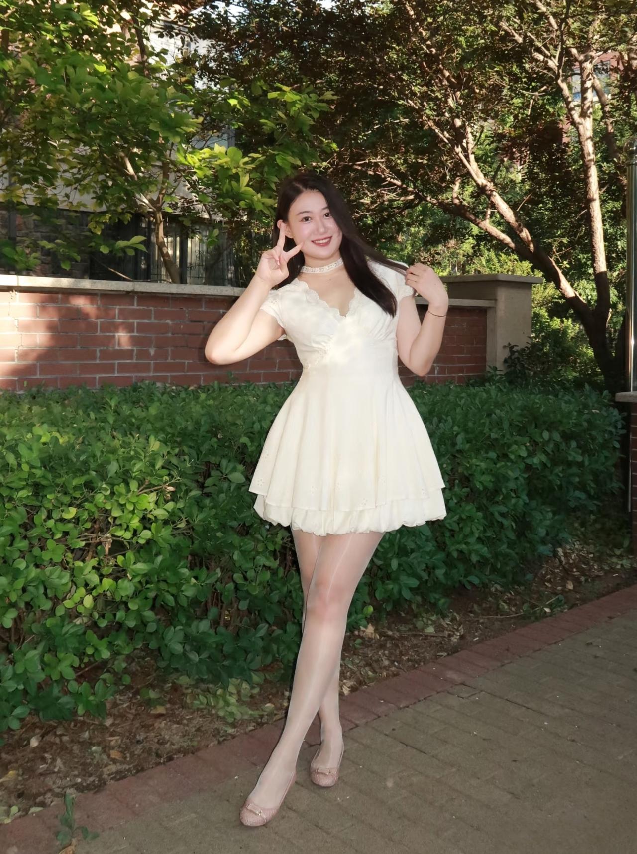 阳光明媚的午后，漂亮的少女在绿意盎然的背景下，摆出俏皮的V字手势，洋溢着青春阳光