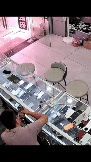 这个手机店老板真是大意了！
两名年轻男孩进店假装挑选手机。
他们趁着老板转身的功