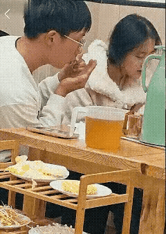 这个男孩对这个女孩好像是挺好，夹起一块肉来，感觉这块肉有点热，于是就用嘴吃这块肉