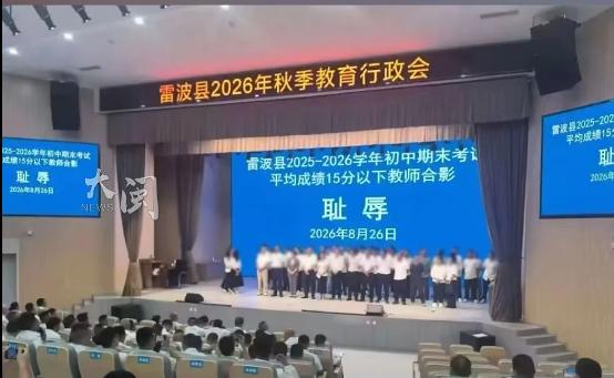 20 多名老师被请上台，在写着 "耻辱" 两个大字的屏幕前合影。台下坐满了人，台