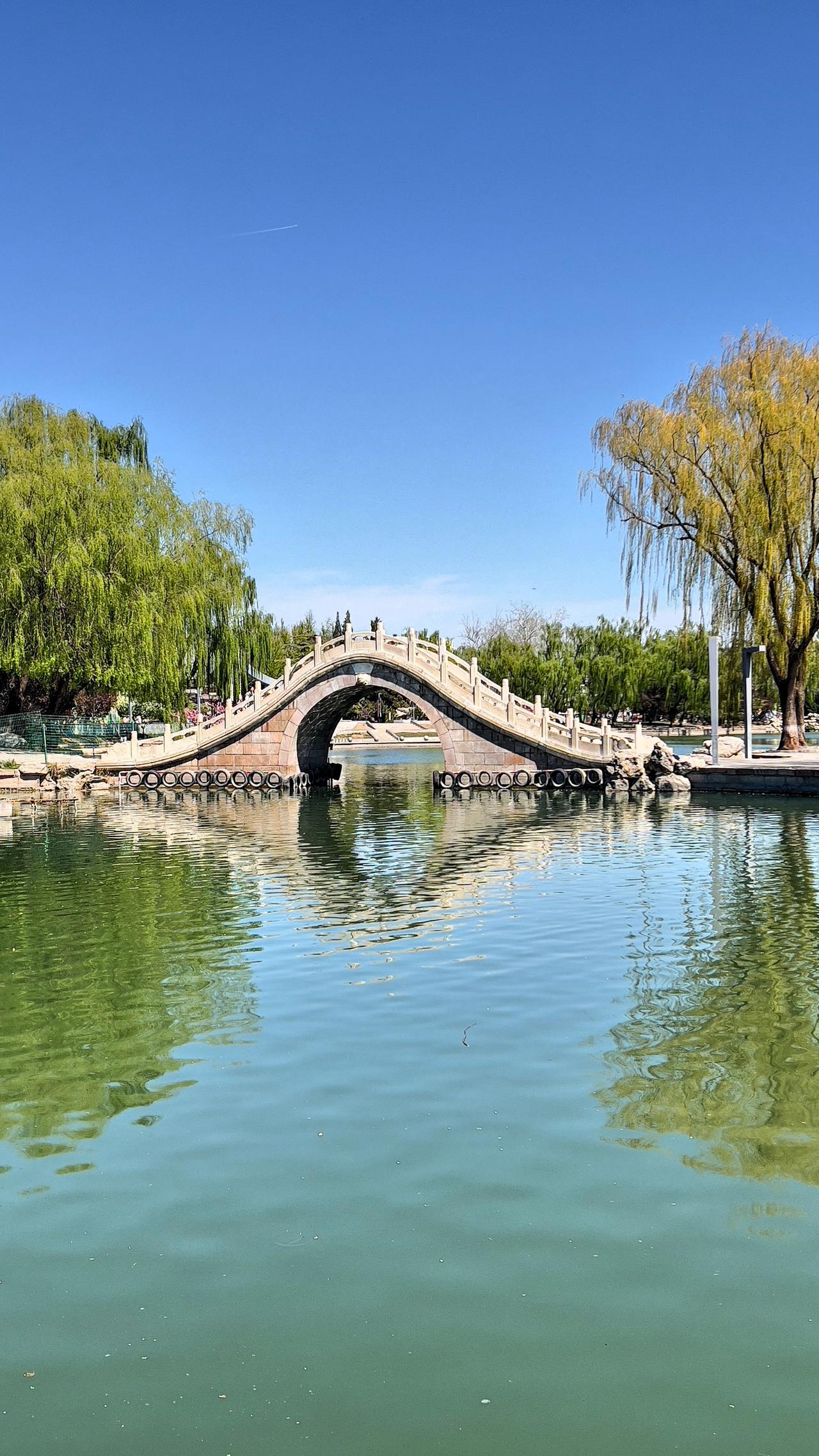 分享一下你随手拍下的照片春日赏景：静谧湖畔，碧水蓝天，绿树掩映，古桥横跨，龙潭湖